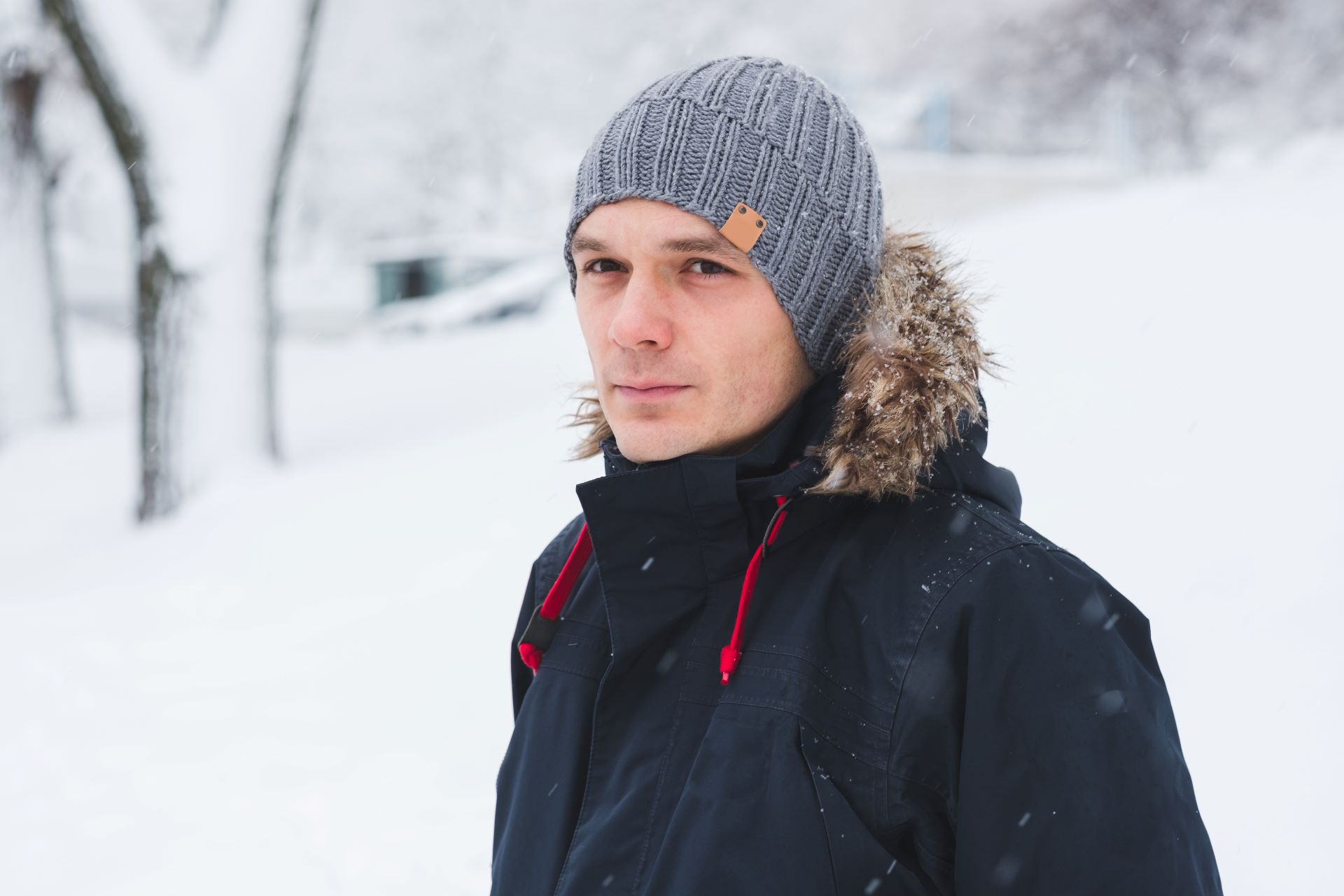 Mann mit grauer Alpaka Mütze im Schnee