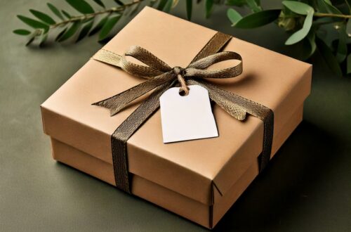 Geschenkschachtel in Naturfarbe mit brauner Schleife und Etikett auf grünem Hintergrund