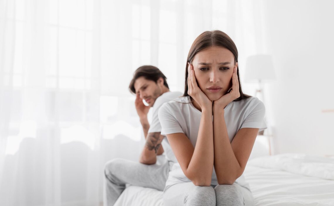 Junges Paar mit gesundheitlichen Sorgen auf dem Bett