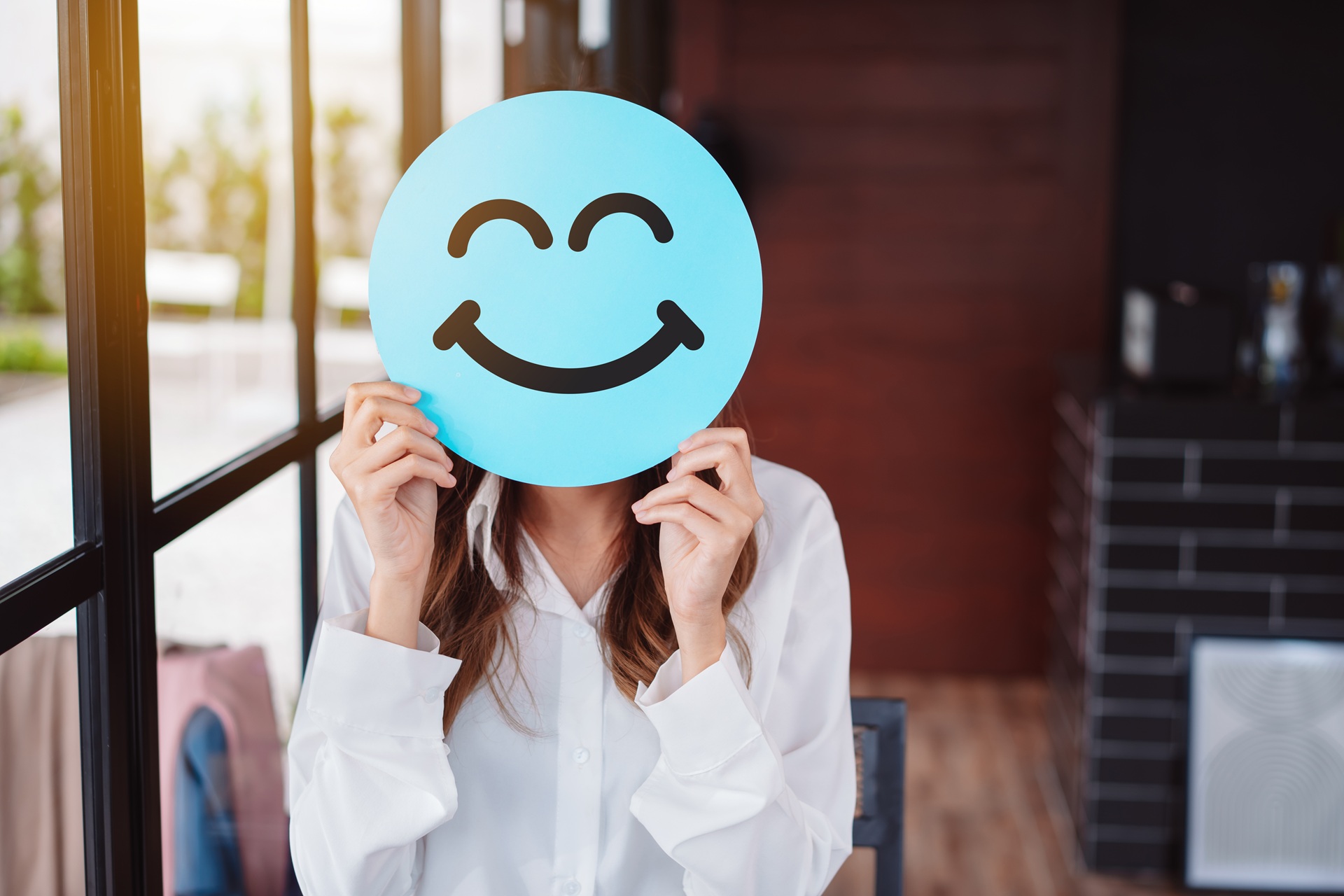 Frau verdeckt Gesicht mit blauem Smiley | Enthärtungsanlage