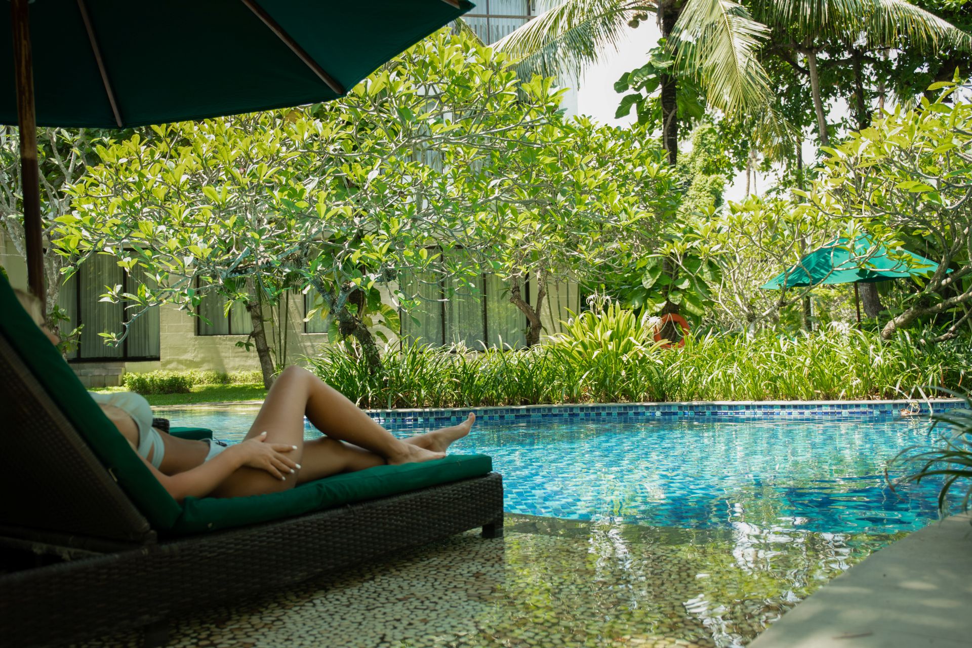 frau entspannt am gartenpool mit gruenen pflanzen und rundpool im hintergrund
