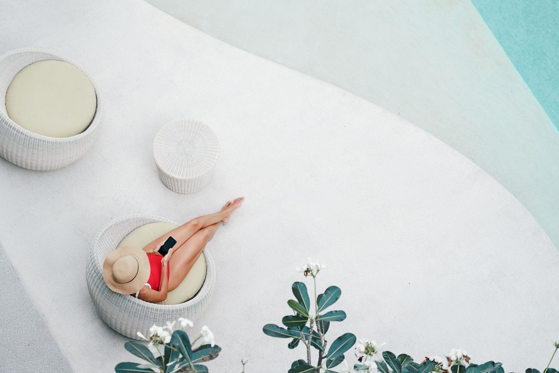 frau in rotem badeanzug sitzt entspannt am rundpool im modernen wellnessbereich zu hause